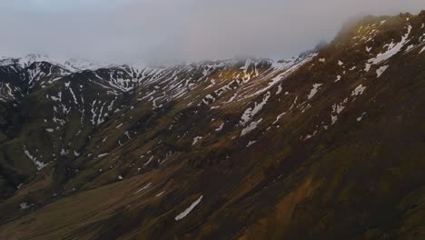 Vista-Aérea-Del-Paisaje-De-Los-Picos-Montañosos-Islandeses-Cubiertos-De-Nieve-Derretida,-En-Un-Día-De-Mal-Humor