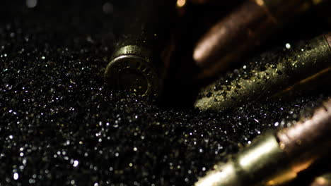 Macro-detail-of-cartridge-falling-on-dark-gunpowder-pile-dust,-close-up
