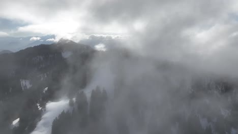 Fliegen-In-Nebligen-Wolken-über-Schneetal-Mit-Kiefern,-Französische-Alpen