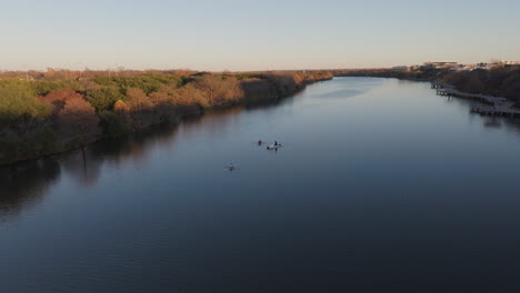 Aerial-shot-of-rowing-boat-on-lake-with-flying-birds-and-trees-at-sunset