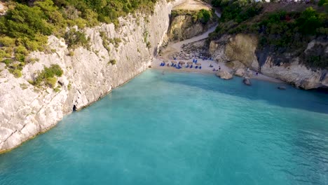 Xigia-beach-in-zakynthos,-turquoise-waters-surrounded-by-cliffs-and-bathers-enjoying-the-sun,-aerial-view