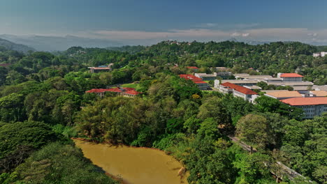 Peradeniya-Sri-Lanka-Aerial-v4-establishing-shot-drone-flyover-Mahaweli-river-capturing-University-campus-ground,-Kandy-suburbs-with-hillside-residential-houses---Shot-with-Mavic-3-Cine---April-2023