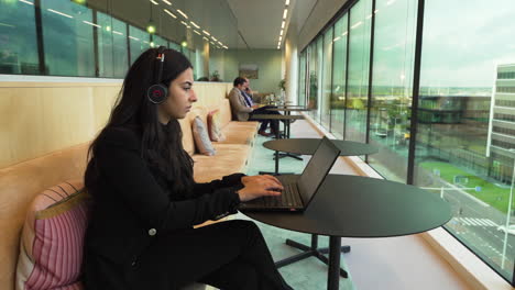 Young-female-business-associate-working-hard-on-her-laptop-in-open-space-with-outside-view