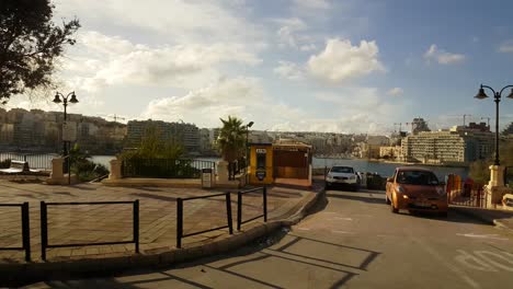 POV-Malta-sidewalk-view-across-seascape-to-hotel-building-along-seascape-coastline
