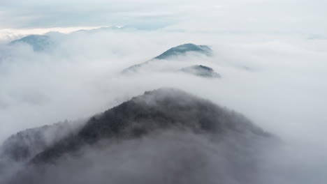 Misty-mountain-peaks-emerging-from-a-sea-of-clouds,-shot-during-early-morning