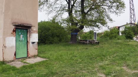 Approaching-drone-shot-of-an-old-building,-a-tree-landmark,-benches,-tower,-in-the-neighborhood-of-Tsarichina-Hole-in-Bulgaria