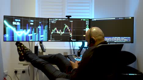A-man-sits-comfortably-in-front-of-three-interconnected-computer-screens,-representing-the-idea-of-engaging-in-home-based-or-day-trading-activities