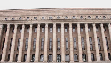 Weite-Aufnahme-Der-Fassade-Des-Parlamentsgebäudes-In-Helsinki-An-Einem-Bewölkten-Tag,-Keine-Menschen-Zu-Sehen,-Imposante-Architektur,-Kamera-Nach-Oben-Geneigt