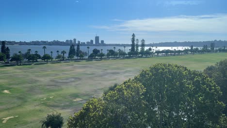 Vea-Arriba-Y-A-Lo-Largo-Del-Parque-Langley-En-Perth,-Australia-Occidental,-Hasta-La-Orilla-Del-Río-Desde-Un-Edificio-De-Oficinas-Con-Un-Cielo-Azul-Y-Una-Vasta-Extensión-De-Césped-Verde-Junto-Al-Río-Swan.