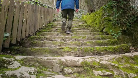 Active-senior-man-ascends-a-steep-flight-of-old-uneven-stone-steps-outdoors
