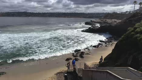 Timelapse-of-people-going-up-and-downstairs-with-waves-crashing-in-the-background-on-a-beautiful-sunny-day-at-La-Jolla-Cove-in-California