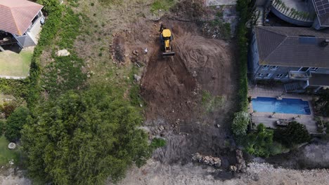 Excavator-digger-working-on-a-plot-and-moving-soil-around-as-seen-from-above