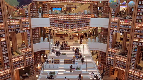 Interior-De-La-Biblioteca-De-Starfield-Suwon-Hall-Con-Un-Entorno-De-Estanterías-De-Paredes-Altas-Y-Amplias-Y-Gente-Caminando-Leyendo---Inclinado-Hacia-Arriba