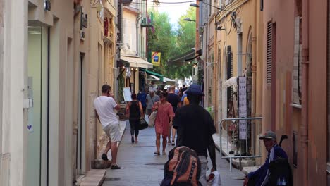 People-walk-on-narrow-walking-street-in-Old-Town-in-Antibes,-France