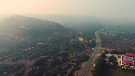 Aerial-Drone-shot-of-a-village-road-through-forested-hills-during-sunrise-in-Central-India