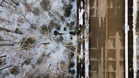 Snow-dusted-trees-on-mount-sequoyah,-ar,-with-a-road-adjacent,-aerial-view