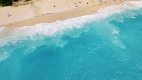 Türkisfarbene-Wellen-Plätschern-Sanft-An-Den-Sandstrand-Von-Myrtos-Auf-Kefalonia,-Griechenland,-Luftaufnahme