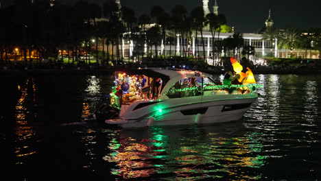 Personas-Disfrazadas-De-Papá-Noel-Montando-Un-Barco-Con-Luces-Navideñas-Y-Adornos-Por-La-Noche