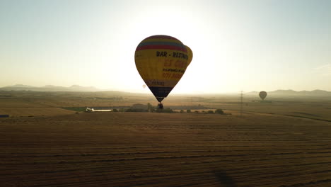 Sunlit-hot-air-balloons-flight-over-Mallorca-agricultural-farmland-in-the-morning-sunrise