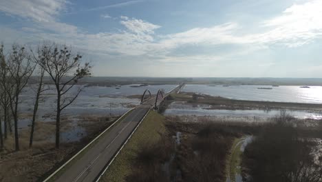 Ramas-Carretera-Puente-Agua-Desbordamiento-Inundación-Día-Soleado-Nubes-Aéreas