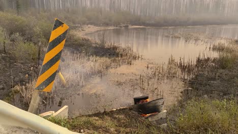 Señal-De-Advertencia-De-Peligro-Con-Rayas-Diagonales-Amarillas-Y-Negras-Junto-A-Una-Quema-De-Madera-Durante-Un-Incendio-Forestal