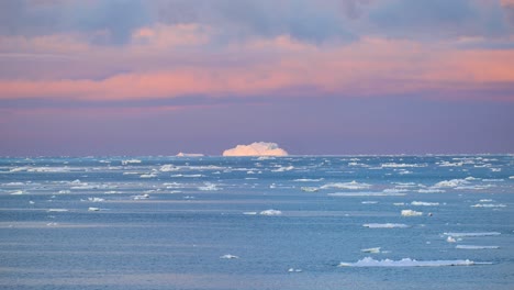 Iceberg-En-La-Antártida-Iluminado-Por-El-Sol-Poniente-Y-Nubes-Coloridas