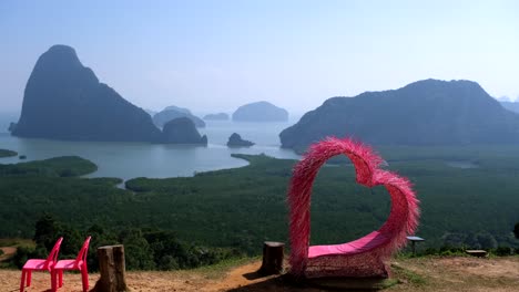 Ein-Atemberaubender-Filmischer-Ausblick-In-4K-Auflösung-Zeigt-Eine-Malerische-Szene-Mit-Einem-Ruhigen-See,-Eigenartigen-Felsen-Unterschiedlicher-Größe,-Einer-Markanten-Rosa-Herzform-Und-Zwei-Plastikstühlen