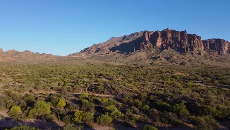 Dirt-roads-in-desert-landscape-leading-to-mountain-range-during-sunset-in-Arizona