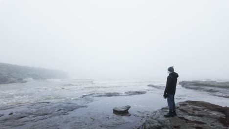 Young-boy-standing-on-the-rocks-on-a-coastal-landscape