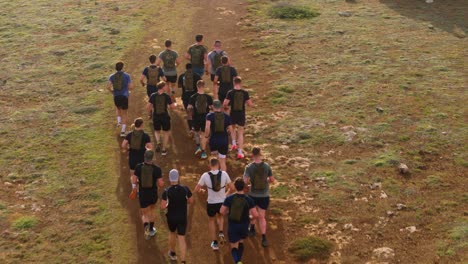 Gruppe-Von-Weißen-Europäischen-Kaukasischen-Und-Dunkelhäutigen-Mischlingen-Männer-Tragen-Trailrunning-Wasserpackungen,-Während-Sie-Entlang-Der-Unbefestigten-Straße-Laufen