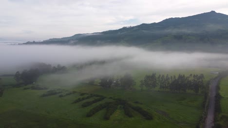 Langsam-Bewegter-Drohnenclip-über-Einem-Grünen-Feld-Mit-Dem-Vulkan-Pasochoa-Im-Hintergrund-In-Neblina,-Machachi-In-Equador