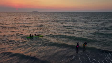 Children-having-fun-in-water-of-ocean-at-sunset
