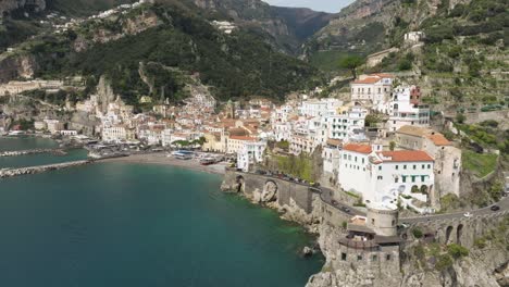 Amalfi-coast-with-clear-blue-water-and-cliffside-buildings-in-daylight,-aerial-view
