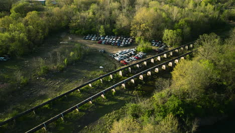 A-junkyard-with-rows-of-cars-in-fayetteville,-ar,-surrounded-by-lush-greenery,-aerial-view
