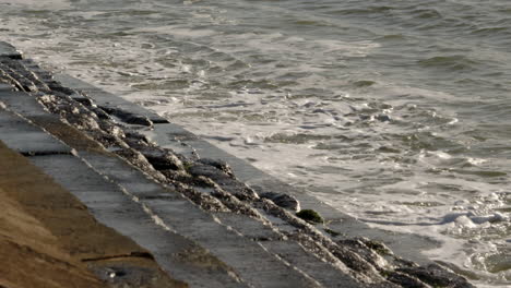 Toma-En-Cámara-Lenta-De-Olas-Rompiendo-Contra-Las-Defensas-Marítimas-En-Milford-On-Sea.