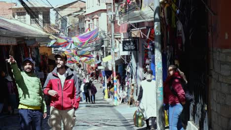 Visitors-walk-charming-narrow-cobble-stone-street-in-La-Paz,-Bolivia