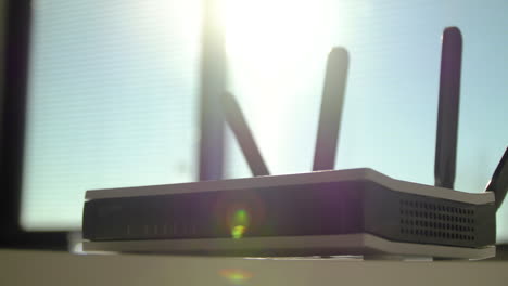 Beautiful-slow-motion-of-a-wifi-router-with-stunning-sunlight-behind-it,-closeup