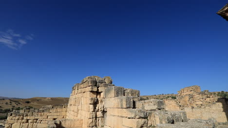 La-Luz-De-La-Mañana-Se-Proyecta-Sobre-Las-Ruinas-Romanas-De-Dougga-Contra-Un-Cielo-Azul-Claro,-Mostrando-La-Arquitectura-Antigua.