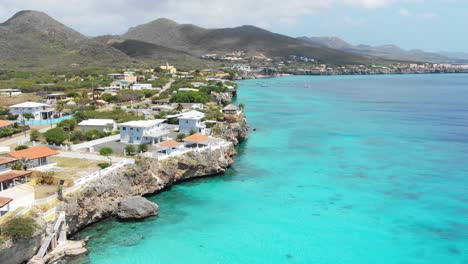 Coastal-town-on-Playa-Kalki,-Curaçao-with-turquoise-waters-and-clear-skies,-aerial-view