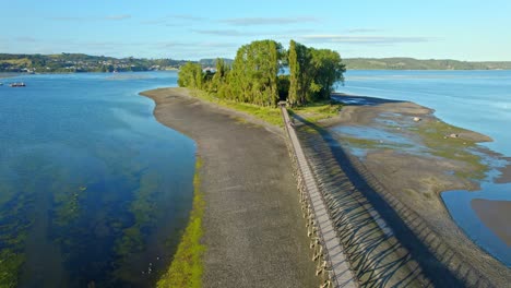 Aerial-view-around-people-walking-to-the-Aucar-Island,-in-sunny-Chiloe,-Chile