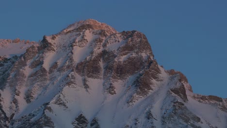 Mit-Einer-Drohne-Aufgenommenes-Filmmaterial-Zeigt-Den-ätherischen-Charme-Des-Sonnenaufgangs,-Der-Die-Silhouette-Einer-Schneebedeckten-Bergkette-Erhellt
