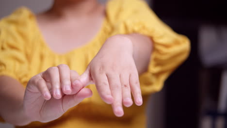Close-up-of-a-woman-in-yellow-shirt-who-is-stretching-while-squeezing-each-finger-of-her-left-hand-to-relieve-her-from-pain