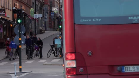 Red-city-bus-turns-on-street-with-bike-traffic-in-Stockholm,-Sweden
