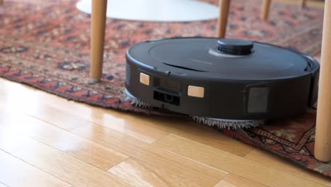 Slow-motion-footage-of-an-autonomous-robot-vacuum-transitioning-from-a-hardwood-floor-to-a-carpet-in-a-living-room