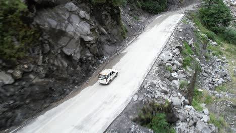 Turistas-En-Un-Vehículo-Todoterreno-Conduciendo-Por-Una-Carretera-De-Montaña-Escarpada-Hacia-Jomsom-En-Nepal---Seguimiento-Aéreo