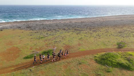 El-Seguimiento-Aéreo-Panorámico-Sigue-A-Un-Gran-Grupo-De-Hombres-Entrenando-Y-Corriendo-Por-Un-Camino-De-Tierra-A-Lo-Largo-De-La-Costa-Caribeña-Vacía.