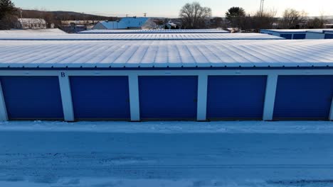 Toma-Aérea-De-Camiones-De-Unidades-De-Garaje-De-Alquiler-Con-Puertas-Azules-En-Un-Día-Nevado-De-Invierno