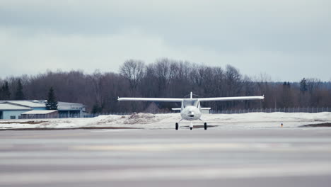 Pequeños-Aviones-Ultraligeros-Blancos-Rodando-Sobre-Plataforma-Asfaltada-Hacia-La-Cámara-Con-Nieve-En-El-Fondo