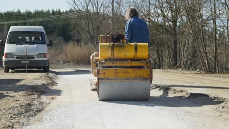 Ein-Männlicher-Arbeiter-Mittleren-Alters-Bedient-Einen-Handbetriebenen-Mini-Straßenwalzenverdichter,-Der-Den-Boden-Für-Eine-Neue-Straße-Glättet.