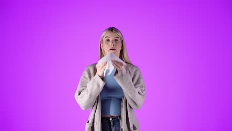 Woman-feeling-unwell,-sneezes-into-tissue,-isolated-pink-studio-background